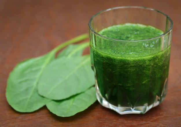 Frullato di purè di spinaci in un bicchiere su superficie di legno