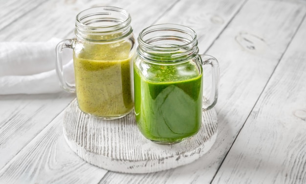 Frullato di spinaci e kiwi in barattoli di vetro sulla tavola di legno