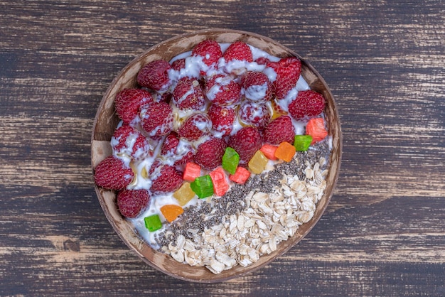 Frullato in ciotola di cocco con lamponi farina d'avena frutta candita e semi di chia per colazione primo piano Il concetto di mangiare sano superfood