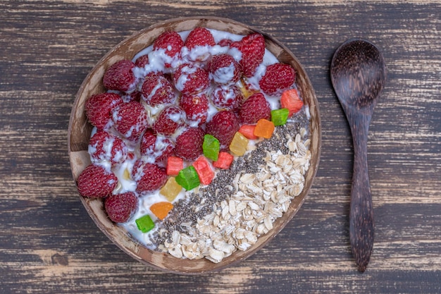 Frullato in ciotola di cocco con lamponi farina d'avena frutta candita e semi di chia per colazione primo piano Il concetto di mangiare sano superfood