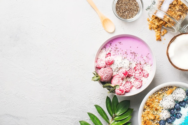 Frullato rosa e blu in una ciotola con pitaya, fragole e lamponi