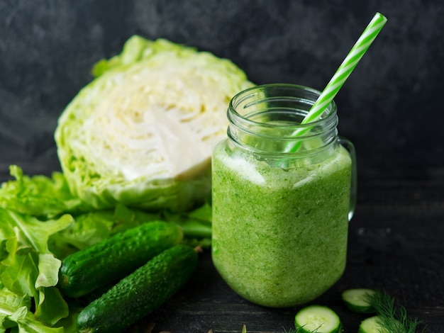 Frullato verde con cetrioli, cavoli e verdi salutari sul tavolo