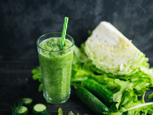 Frullato verde con cetrioli, cavoli e verdi salutari sul tavolo