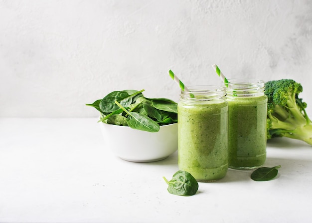 Frullato verde in vasetto di vetro con paglia e spinaci e broccoli