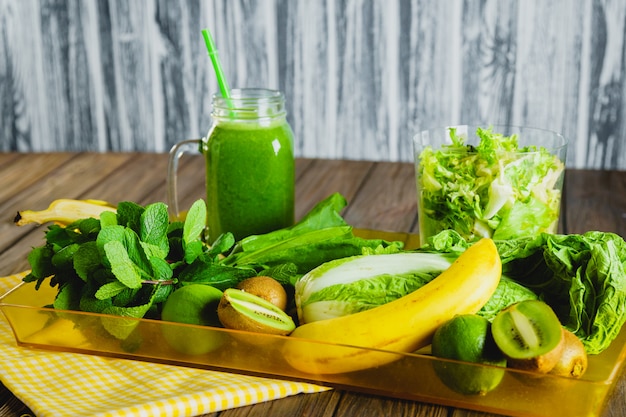 Frullato verde mescolato con gli ingredienti sulla tavola di legno