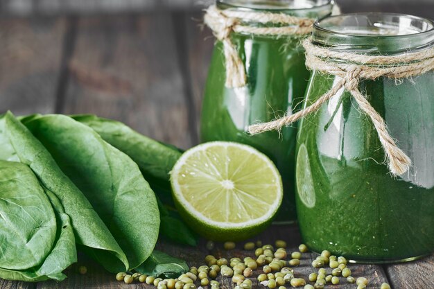 Frullato verde mescolato con ingredienti sul bordo di pietra, fuoco selettivo della tavola di legno