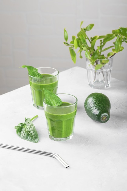 Frullato verde sano con banana avocado spinaci e latte vegano in due bicchieri e fresco