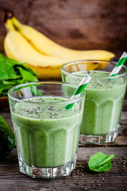 Frullato verde sano con banana, avocado, spinaci e semi di chia in vetro su fondo rustico