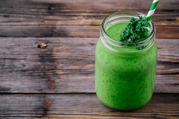 Frullato verde sano con cavolo cappuccio in barattolo di vetro su fondo di legno rustico