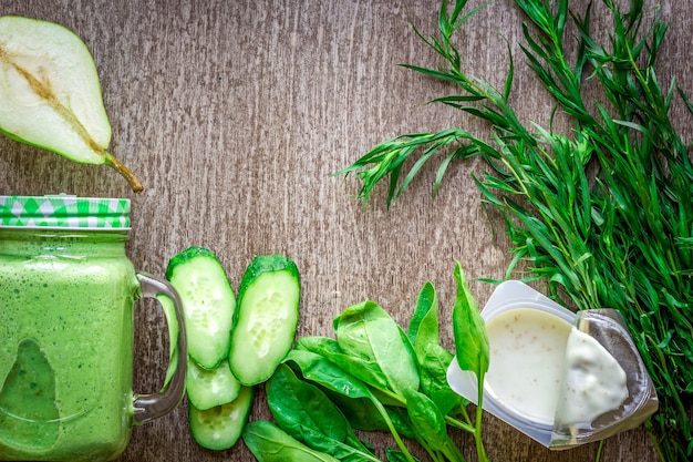 Frullato verde sano con spinaci in una tazza contro su fondo di legno