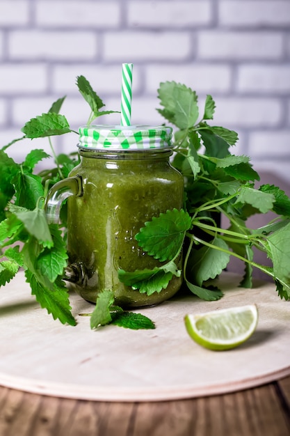 Frullato verde sano degli spinaci in barattolo sulla tavola di legno, fuoco selettivo. Avvicinamento.