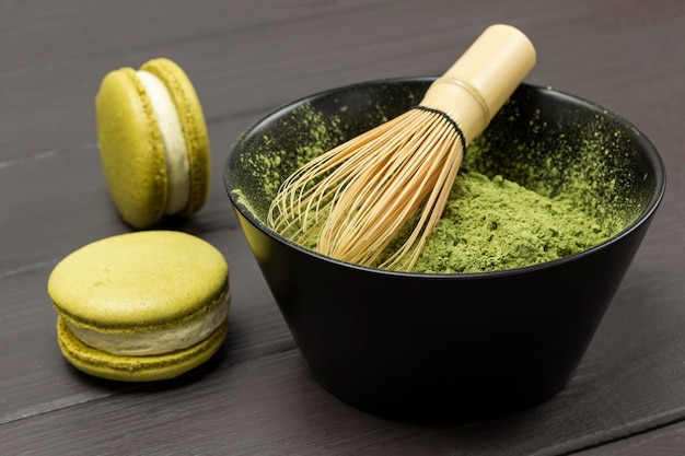 Frusta di bambù in una ciotola con polvere di matcha Due torte di maccheroni