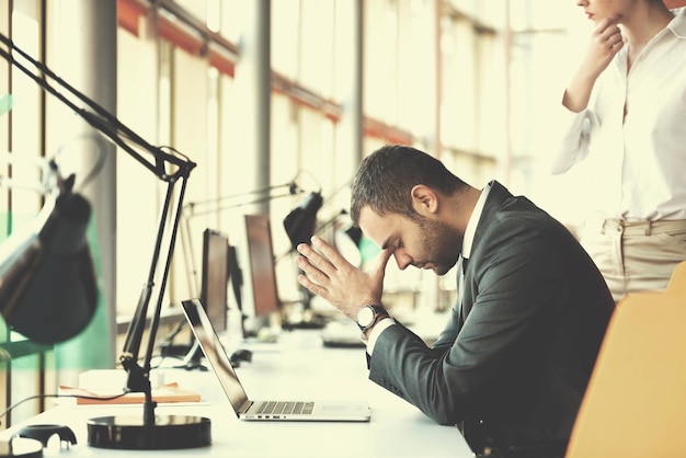 frustrato giovane uomo d'affari che lavora al computer portatile in ufficio