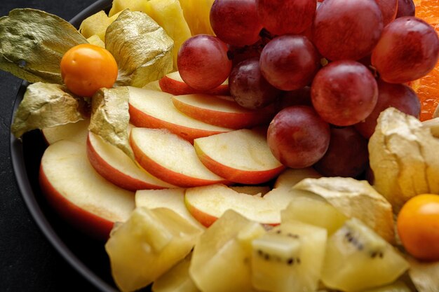 Frutta a fette su un piatto da dessert su uno sfondo scuro