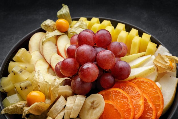 Frutta a fette su un piatto da dessert su uno sfondo scuro