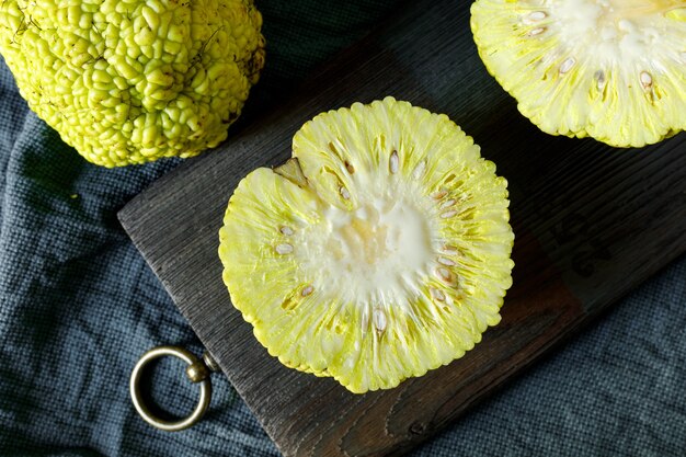 frutta affettata di maclura pomifera su vecchio tagliere di legno e panno blu scuro