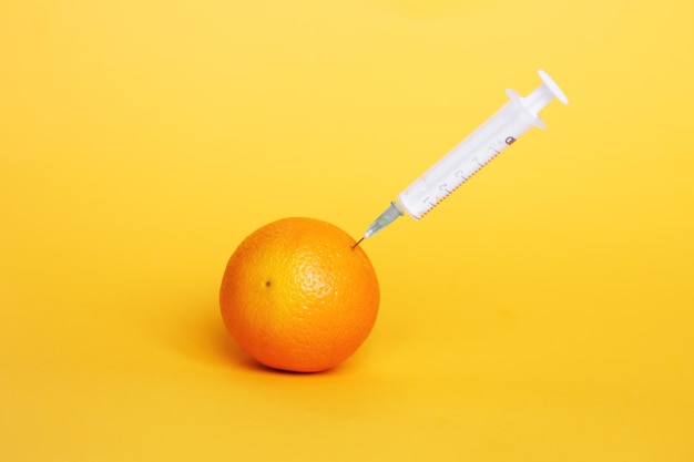 Frutta arancione con liquido di estrazione a siringa con concetto di cosmetici naturali anti invecchiamento di vitamina C
