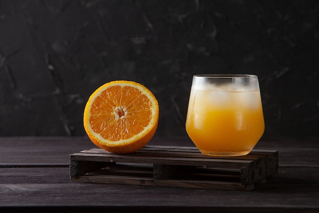 Frutta arancione e bicchiere di succo su fondo di legno scuro