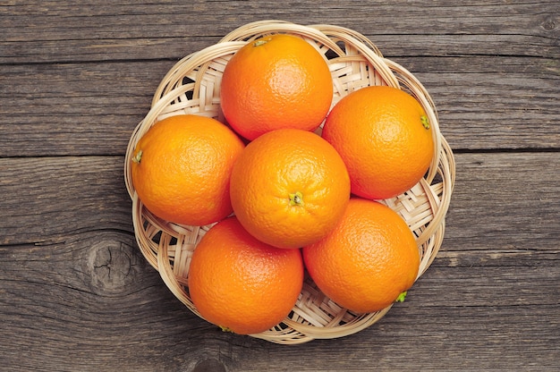 Frutta arancione in piatto di vimini sulla tavola di legno dell'annata. Vista dall'alto