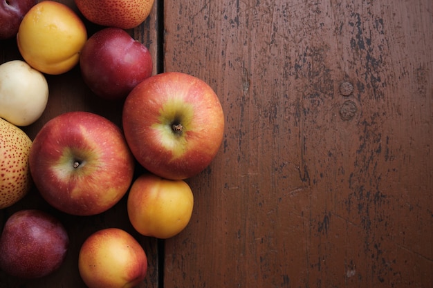 Frutta autunnale su un tavolo di legno Mele pere prugne albicocche su sfondo rosso scuro