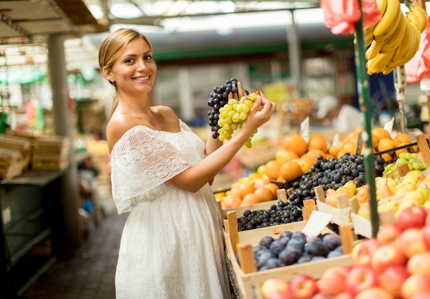 Frutta d&#39;acquisto della giovane donna sul mercato