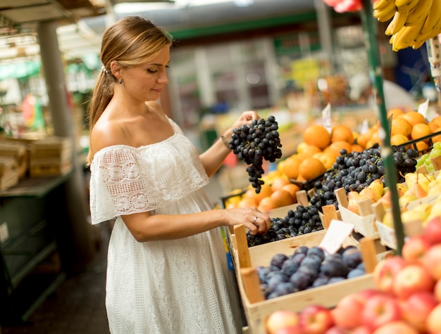 Frutta d&#39;acquisto della giovane donna sul mercato