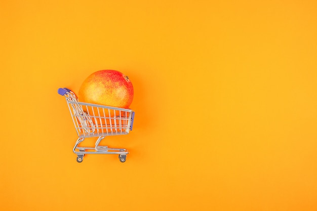 Frutta del mango in carrello su fondo arancio