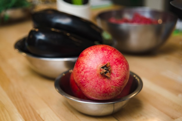 Frutta del melograno in una ciotola di metallo su un tavolo di legno