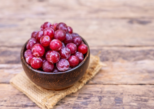Frutta dell'uva rossa nella ciotola di legno sulla superficie vaga