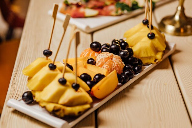 Frutta di ananas tagliata su tavola festiva in legno con candele per la festa di nozze al buio