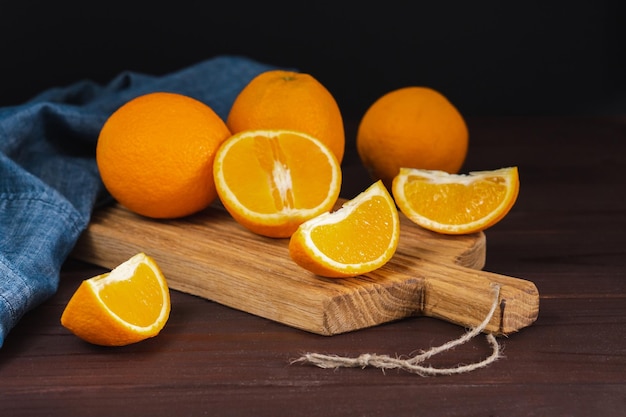Frutta di arance a fette vicino al tessuto denim su tavola di legno Concetto minimo di agrumi di frutta succosa arancione
