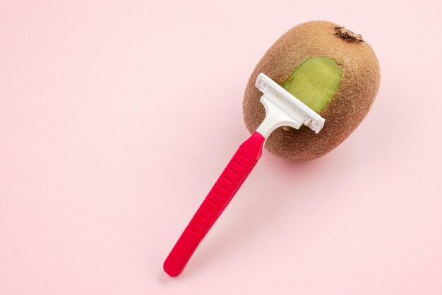 Frutta di kiwi e rasoio su sfondo rosa concetto di rimozione dei capelli concetto minimale creativo con spazio di copia