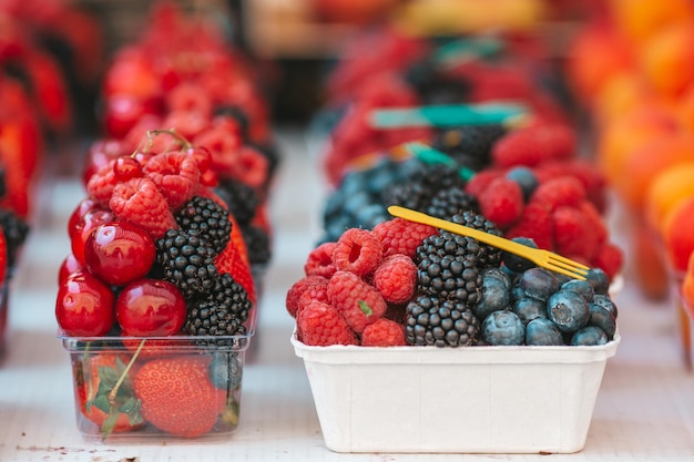 Frutta e bacche sul mercato di strada Mirtilli lamponi fragole ciliegie e more sul mercato Giardinaggio agricoltura raccolto e concetto di foresta