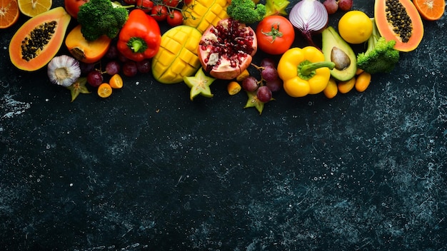 Frutta e verdura cibo sano Frutta e verdura su sfondo di pietra nera Frutta tropicale Vista dall'alto Spazio libero per il testo