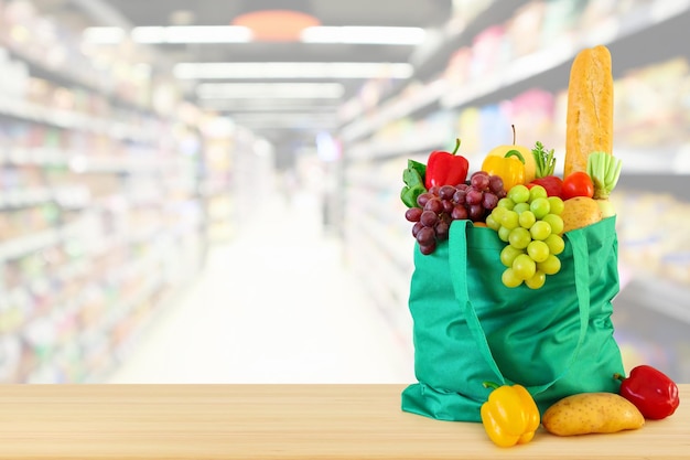 frutta e verdura in borsa della spesa sul piano del tavolo in legno con sfondo supermercato drogheria