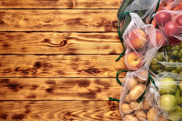 Frutta e verdura in sacchetti ecologici riutilizzabili su fondo di legno