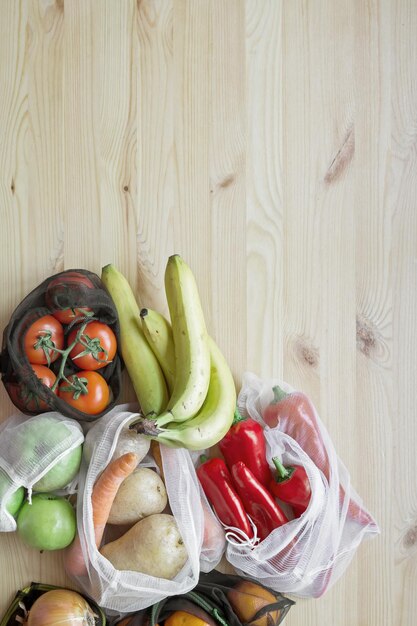 Frutta e verdura in sacchetti riutilizzabili per la spesa su un tavolo di legno Il concetto di zero sprechi e uno stile di vita ecologico Nessuna plastica Vista dall'alto