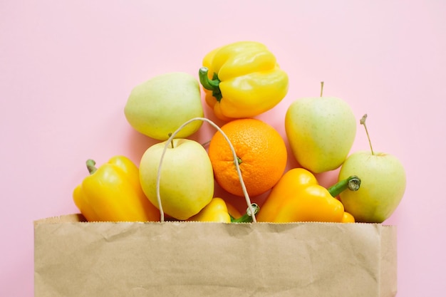 Frutta e verdura in sacchetto di carta su sfondo rosa piatto lay Zero rifiuti shopping senza plastica Acquistare generi alimentari online Ordinare alimenti biologici freschi e farli consegnare in sicurezza