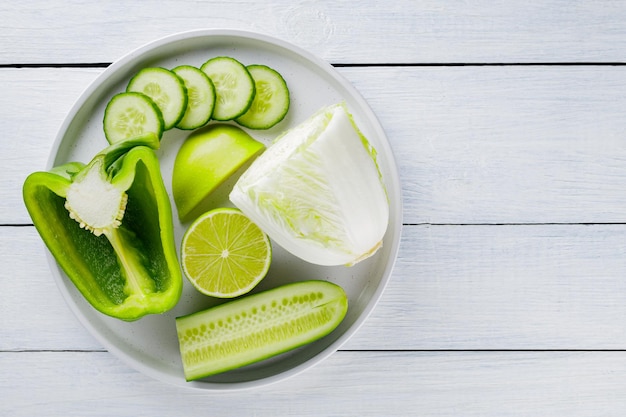 Frutta e verdura verdi affettate su un piatto bianco. Alimento dietetico verde su lavagne bianche. Cibo sano e vegetariano. Vista dall'alto. Copia spazio
