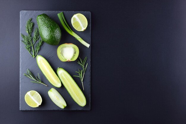 Frutta e verdura verdi su tavola di ardesia Avocado kiwi lime e mela su sfondo scuro