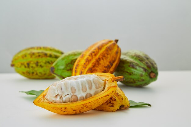 Frutta fresca del cacao con la foglia verde su fondo bianco