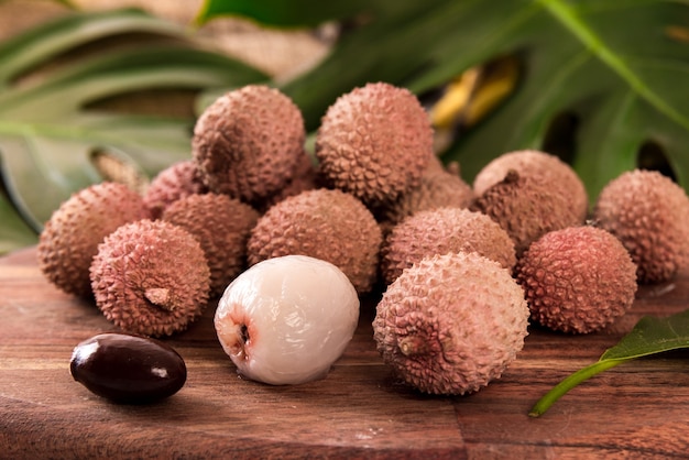 Frutta fresca del litchi organico sul canestro di bambù e sulla vecchia tavola di legno