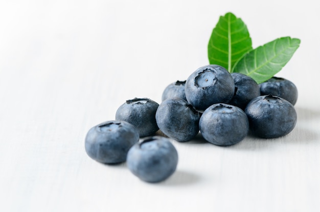 frutta fresca del mirtillo con la foglia su fondo di legno bianco, concetto sano dei friuts