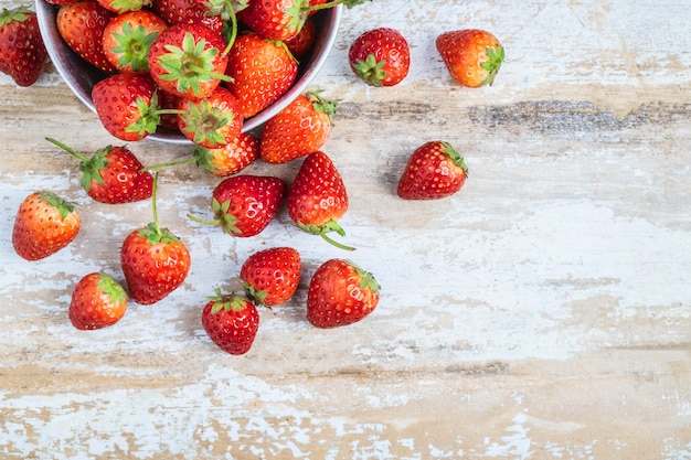 Frutta fresca della fragola in una ciotola su un fondo di legno