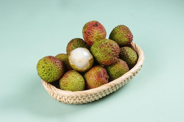 Frutta fresca di litchi verde maturo e litchi sbucciato su una ciotola di rattan