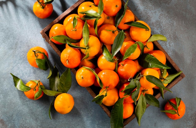 Frutta fresca di mandarini o mandarini con foglie in scatola di legno vista dall'alto