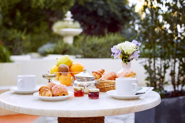 Frutta fresca, dolci, marmellata e caffè su un tavolo all'aperto