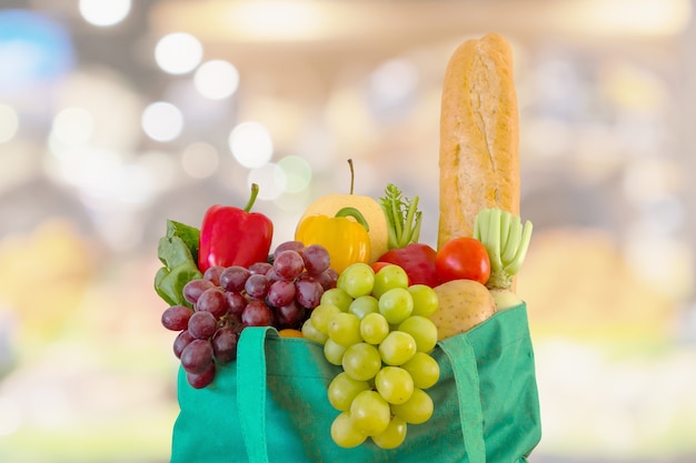 Frutta fresca e verdura in sacchetto della spesa verde riutilizzabile con drogheria del supermercato sfocato sfondo sfocato con luce bokeh