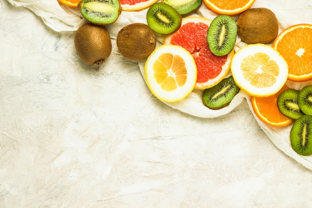 Frutta fresca, pompelmo, limone, arancia, kiwi su uno sfondo di pietra chiara. Copia spazio e una vista dall'alto