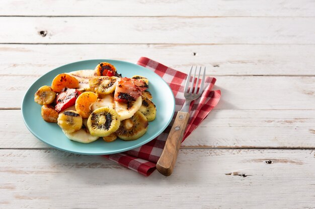 FRUTTA GRIGLIATA su un piatto blu e su un tavolo in legno bianco